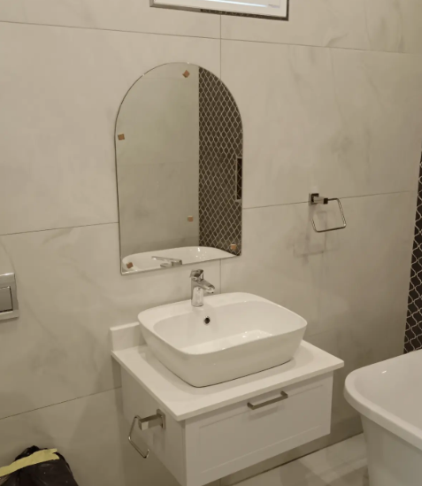 Compact bathroom with wall-hung basin and arched mirror